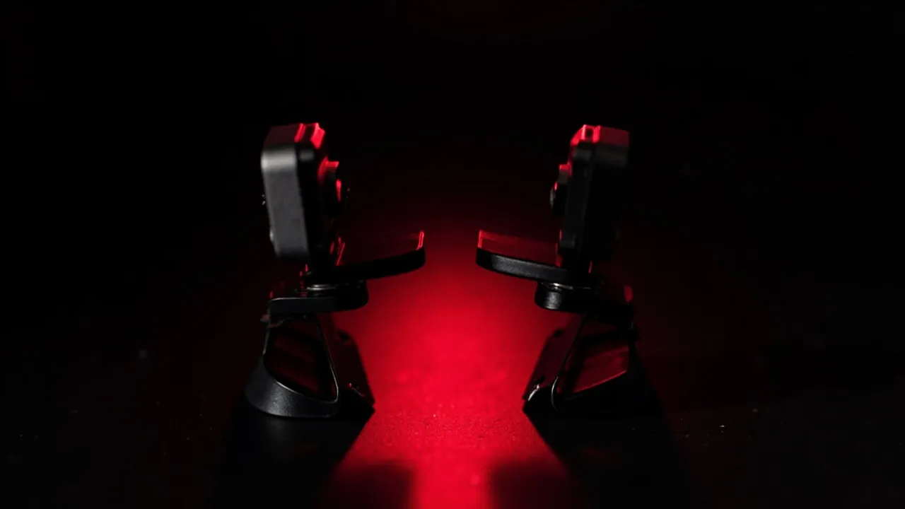 Two small webcams facing each other on a dark surface bathed in red light
