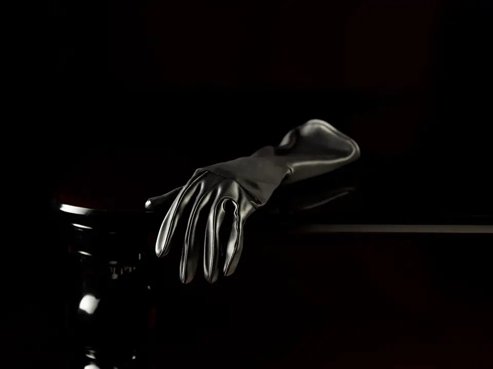 Black latex opera gloves draped over a black lacquered table