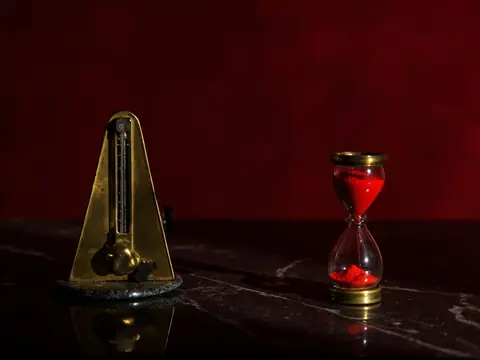 A brass metronome and an hourglass of red sand
